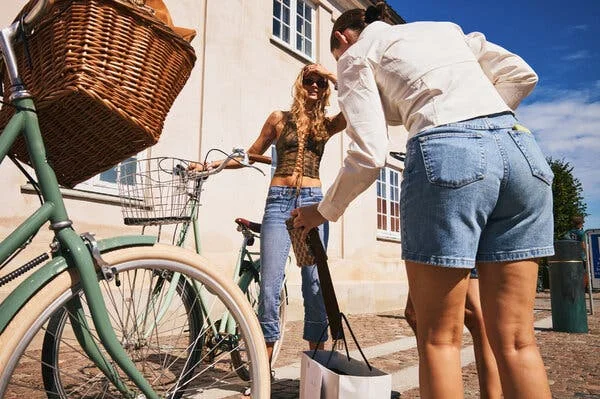 People wearing bluejeans and denim shorts standing near two bicycles with frames in different pale-green shades.