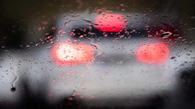 A photo of car tail lights in rain. 