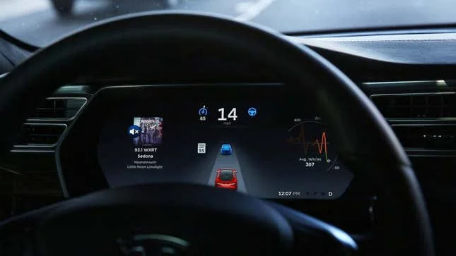 A photo of a dashboard showing Tesla Autopilot running. 