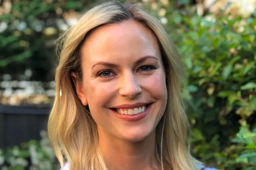 Portrait of a smiling blonde woman wearing a colourful top 