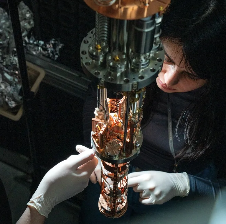 An operator wearing white gloves works on a scanning microscope