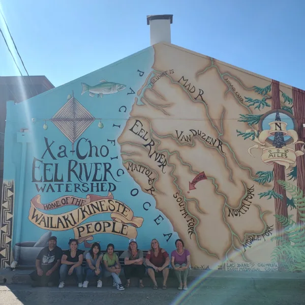 mural with group of people seated against the building