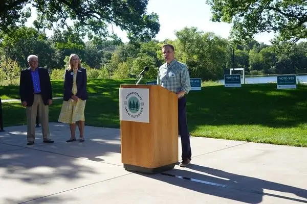 Person stands at wooden podium outside