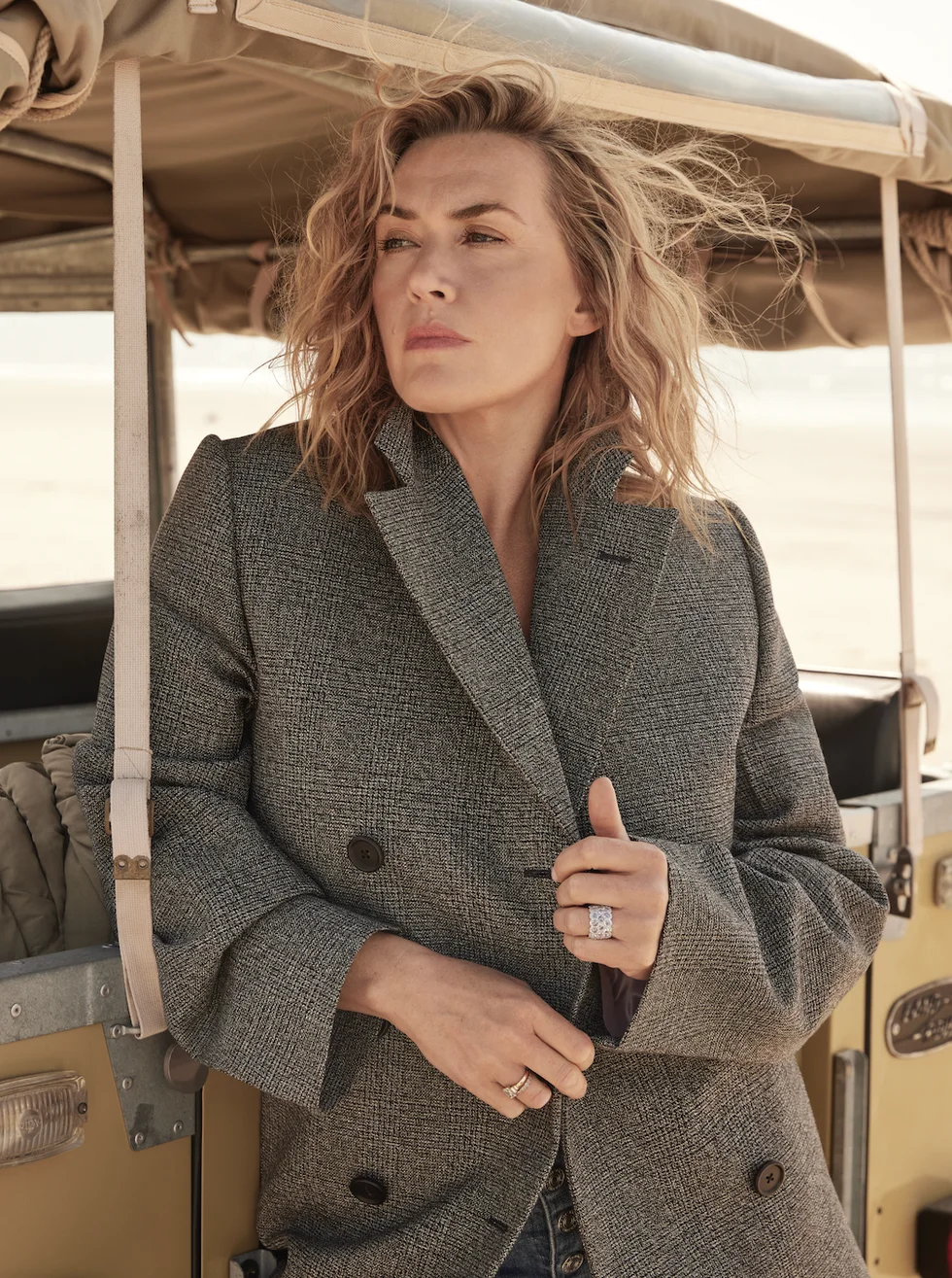 kate winslet poses in a coat by a van