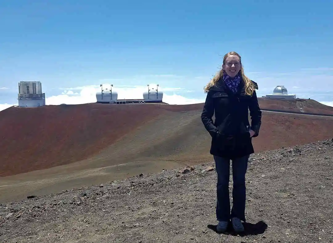 Scientist standing on mountain with telescopes in background