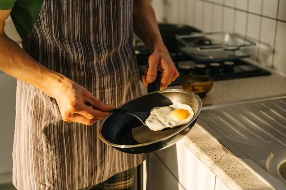 young man cooking in light kitchen at home