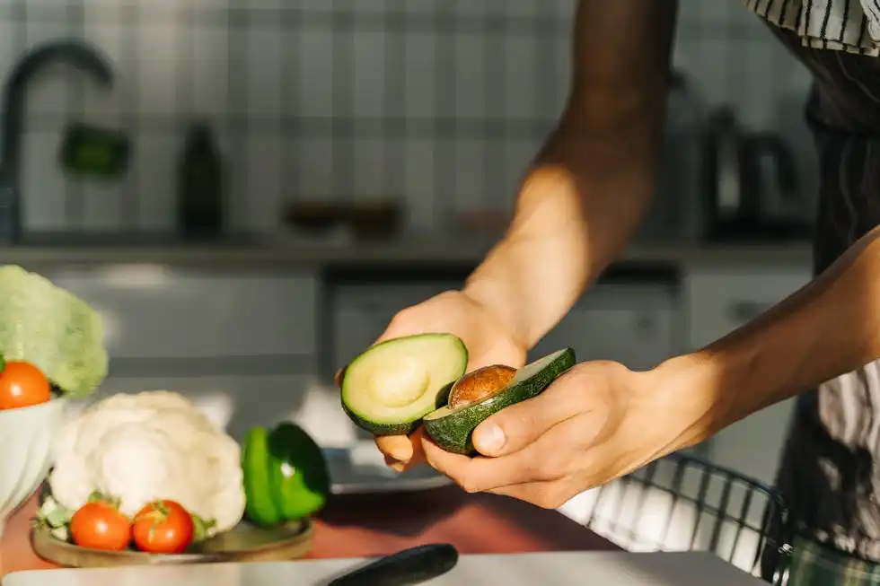 young man cooking guacamole in light kitchen at home hands close up