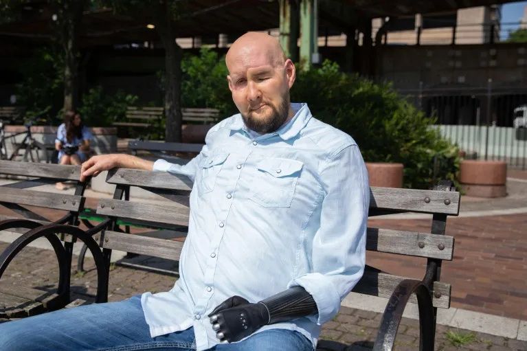 A portrait of Aaron James sitting on a bench outdoors