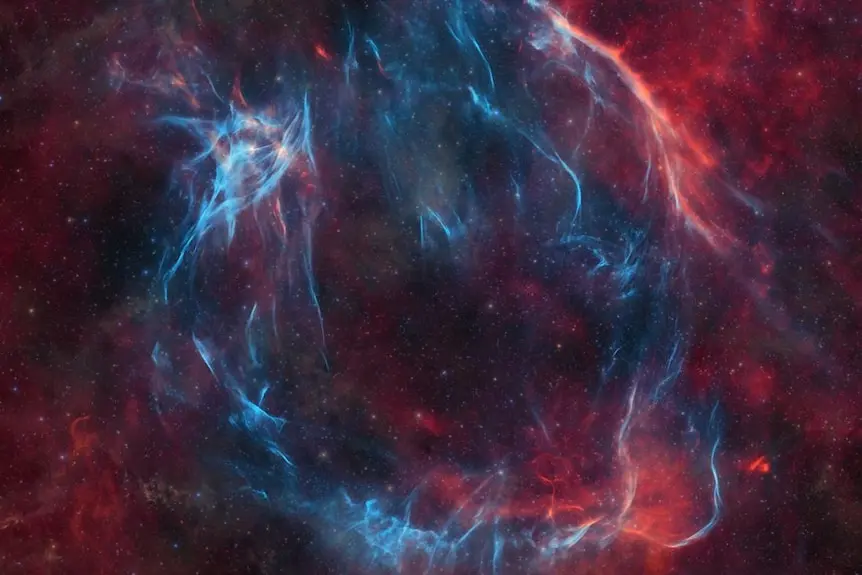 A red and blue image of a supernova in space