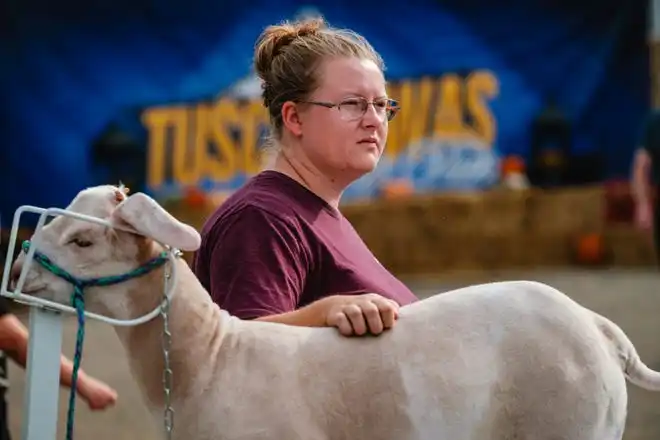 Laryssa Porter, from Port Washington, comforts the market lamb to be shown by her friend, Emmalynne Berger (off camera) at the Tuscarawas County Fair.