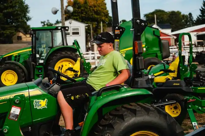 A boy rests on a tractor on display at the Tuscarawas County Fair.