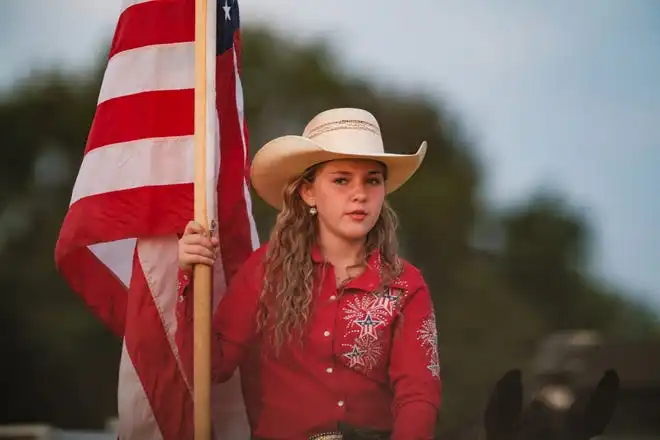 A rodeo participant sits atop her horse with the American Flag at the Tuscarawas County Fair.