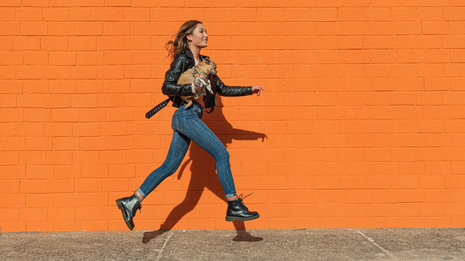 woman wearing leather jacket skipping on a street