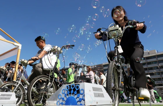 Participants create soap bubbles with bicycles at the Do It For Earth festival at Gwanghwamun Square in Jongno District, central Seoul, on Tuesday. [YONHAP]