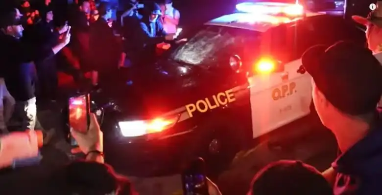 an OPP vehicle drives in a crowd with onlookers taking photos