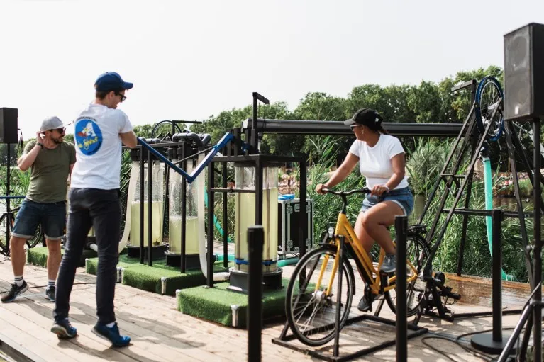 Festival visitors participate in an experiment by pedalling a bike to filter the lake water