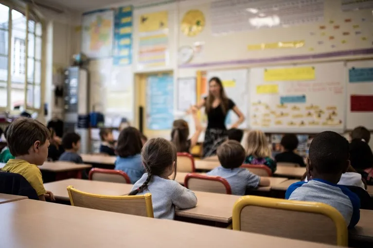 Children listen to their teacher as they sit in a classroom on the first day of the start of the school year, at the Chaptal elementary school in Paris.