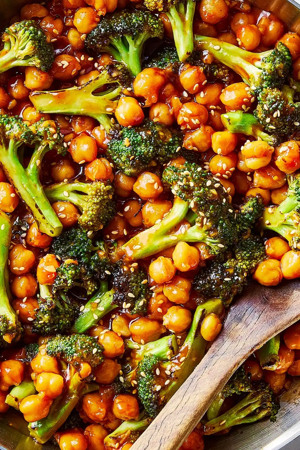 sticky sesame chickpeas and broccoli in a pan with a wooden spoon