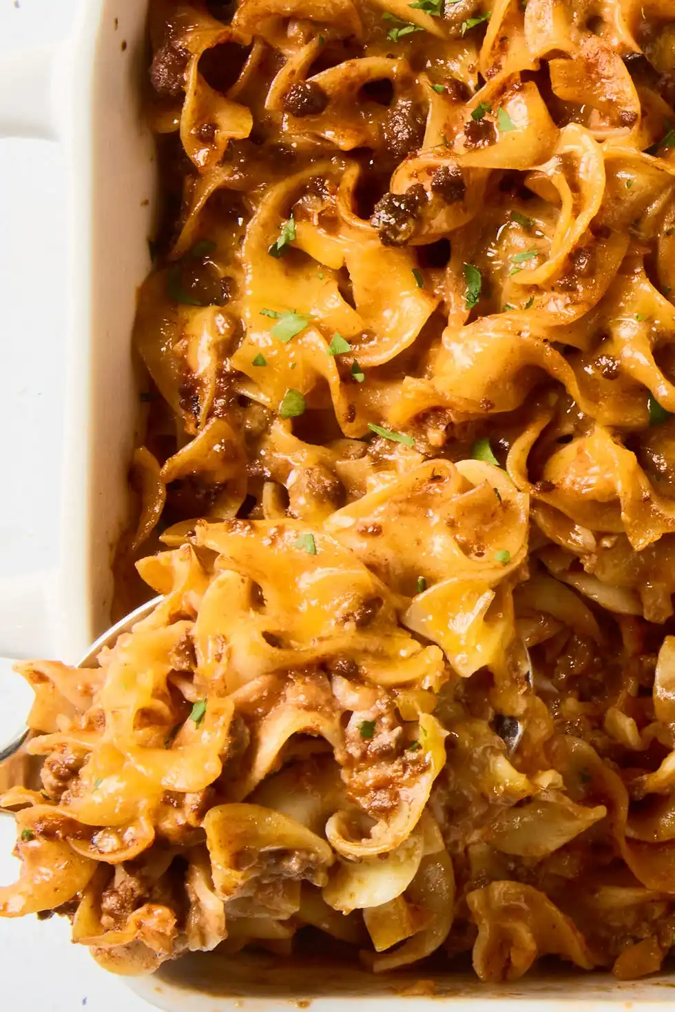 beef noodle casserole topped with cheese in a baking dish