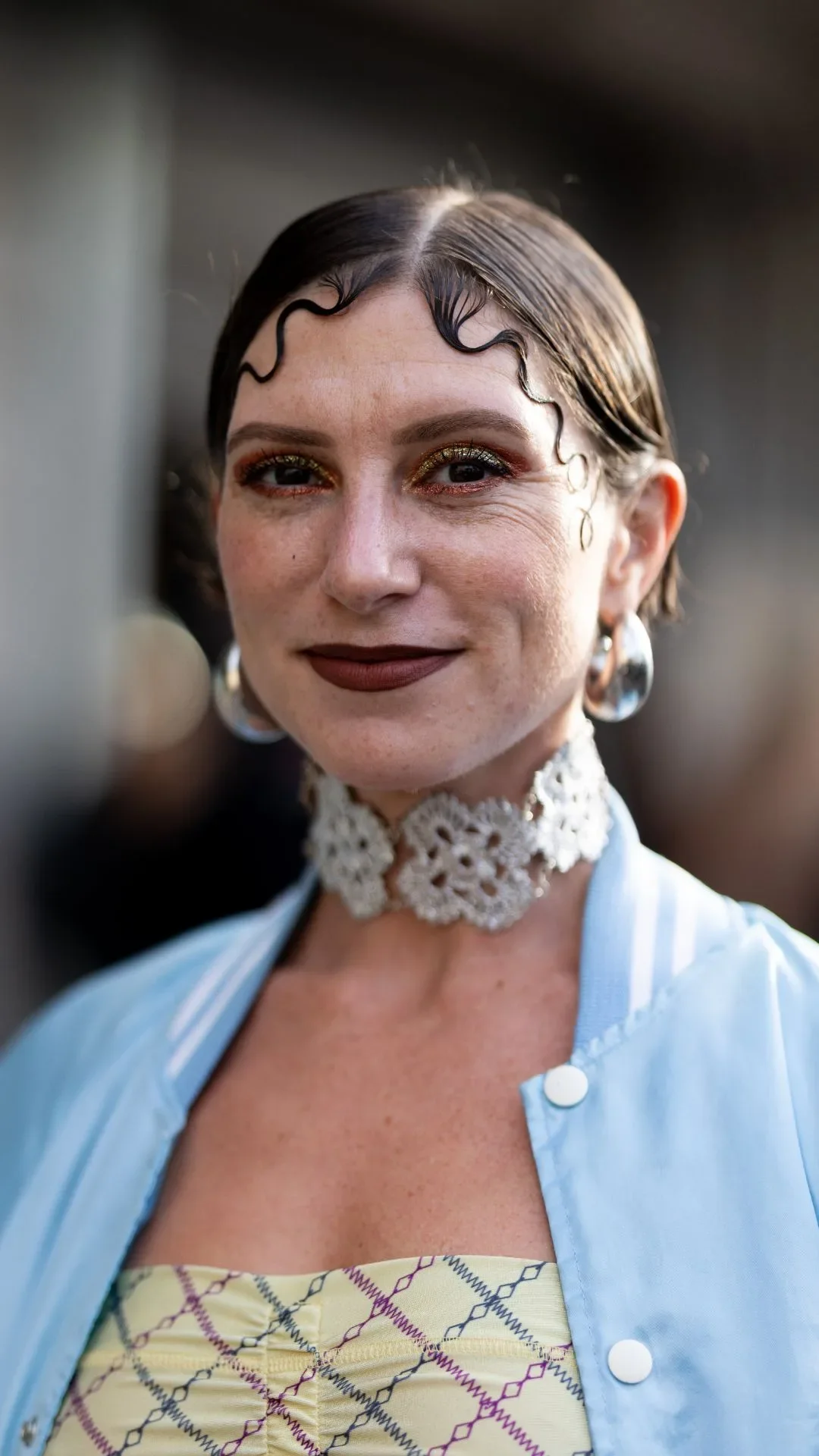 A guest wears silver hoop earrings, a light blue bomber, a silver necklace and a yellow printed top outside Ottolinger show during Womenswear Spring/Summer 2025 as part of Paris Fashion Week on September 29, 2024 in Paris, France.