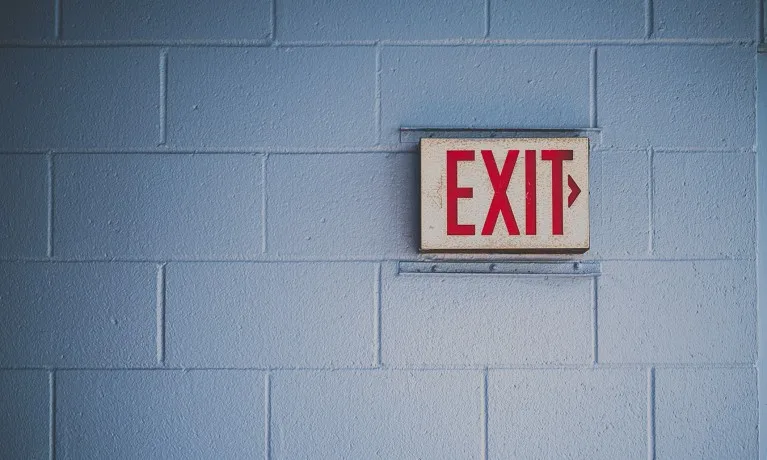 An Exit sign installed on a brick wall.