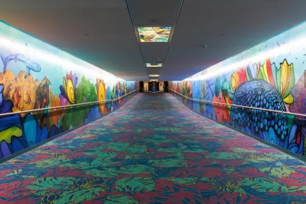 A long pedestrian tunnel features a colorful carpet and wall paneling, making the pedestrian feel like they're underwater.