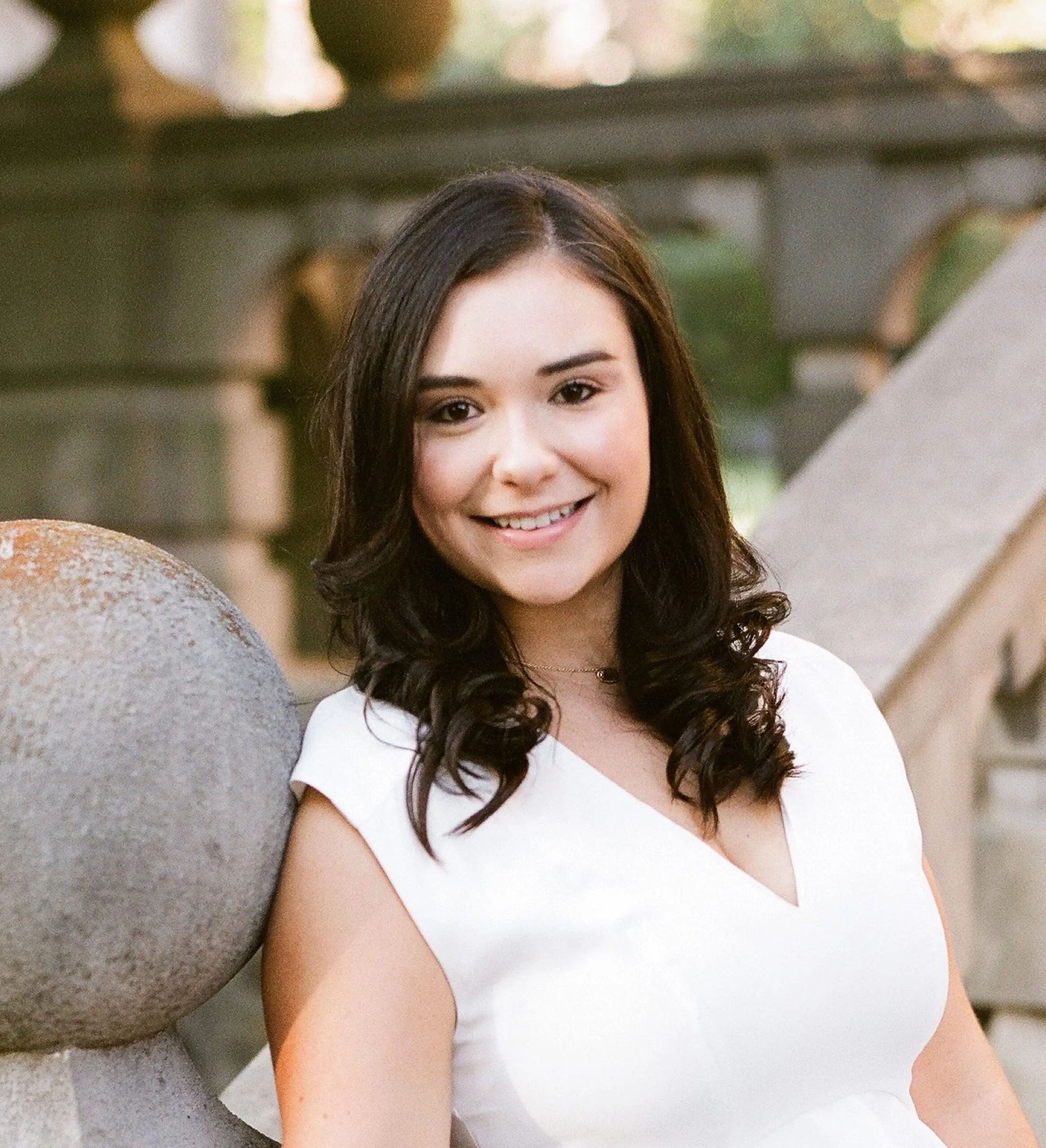 Woman with brown hair and white blouse smiling at camera.