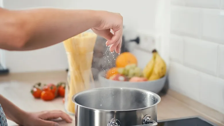 Woman salting boiling water