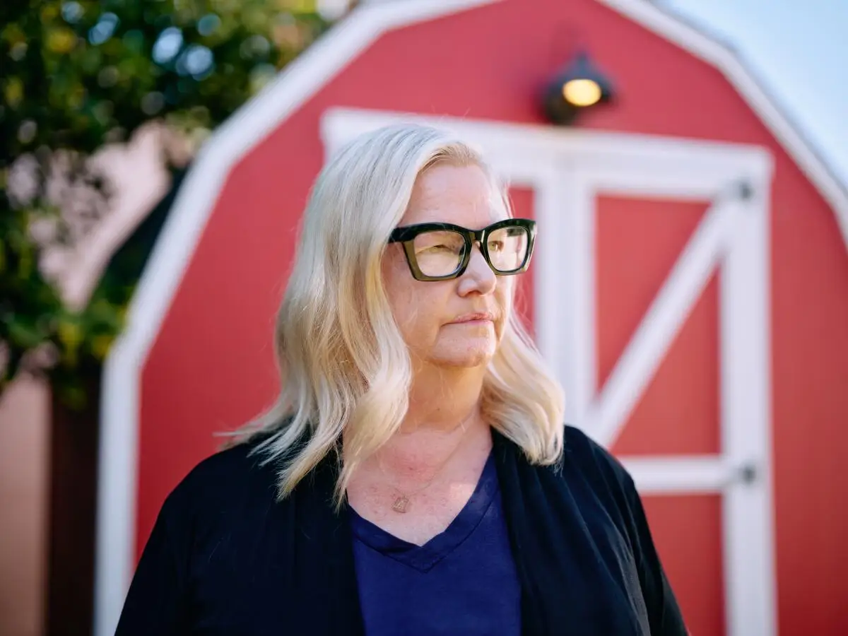 Alyson Dee Moore wearing glasses and standing on front of a red barn