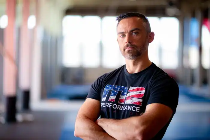 Mike Molloy standing in a gym with his arms folded, looking into the camera.