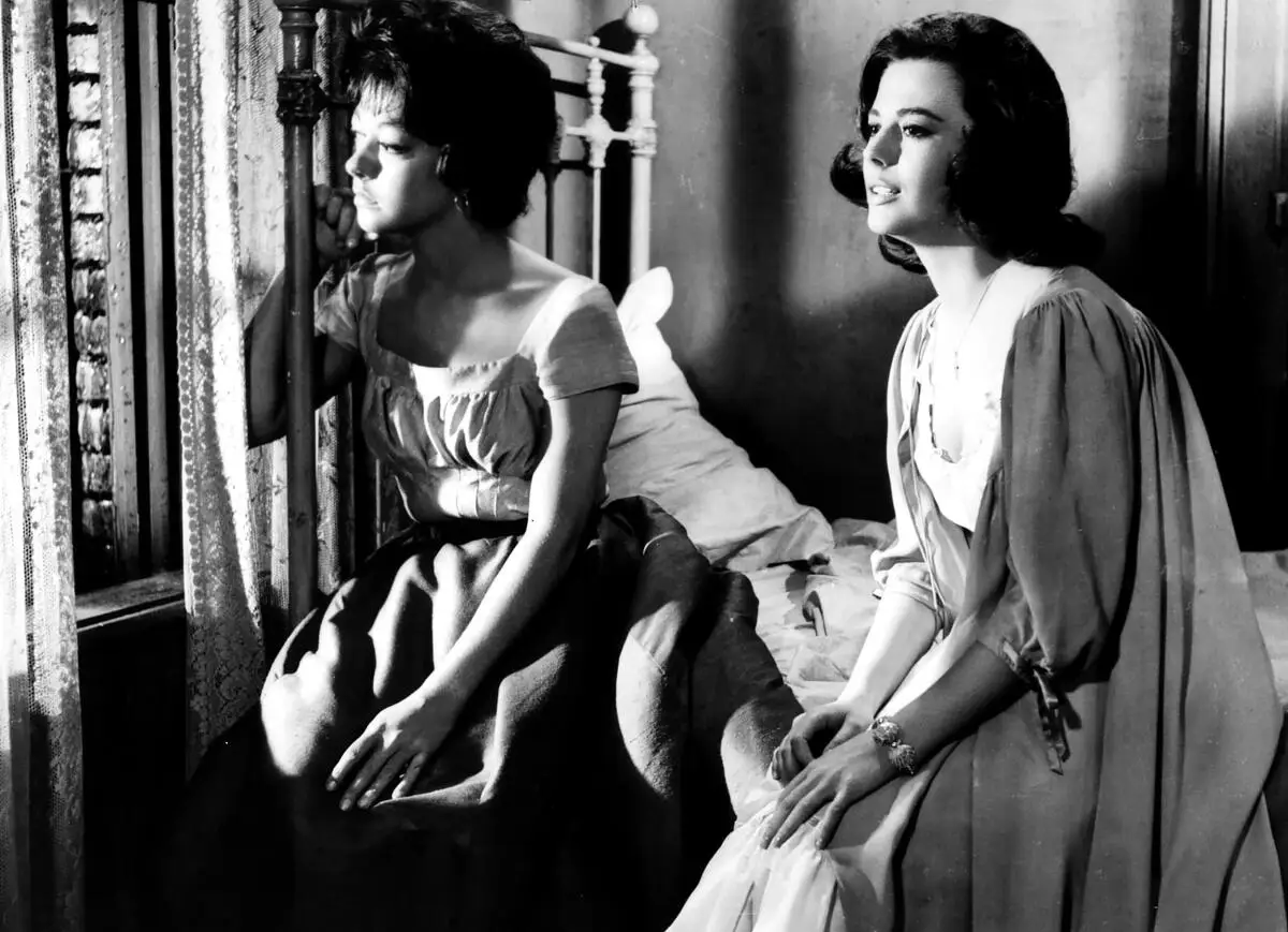 Two women look out a window in a black-and-white film still