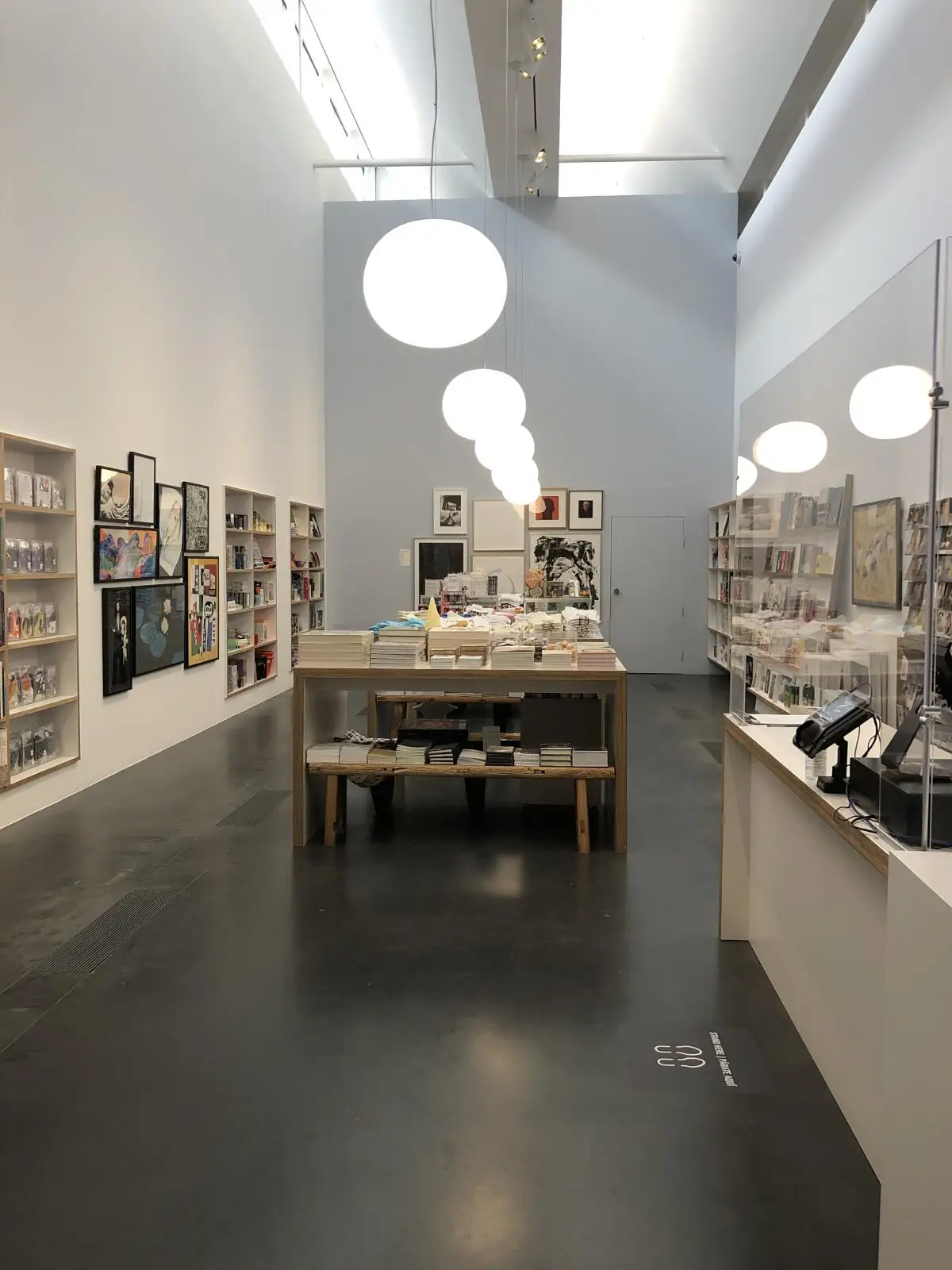 A view of a museum shop shows a narrow space lined with books and other objects for sale. 