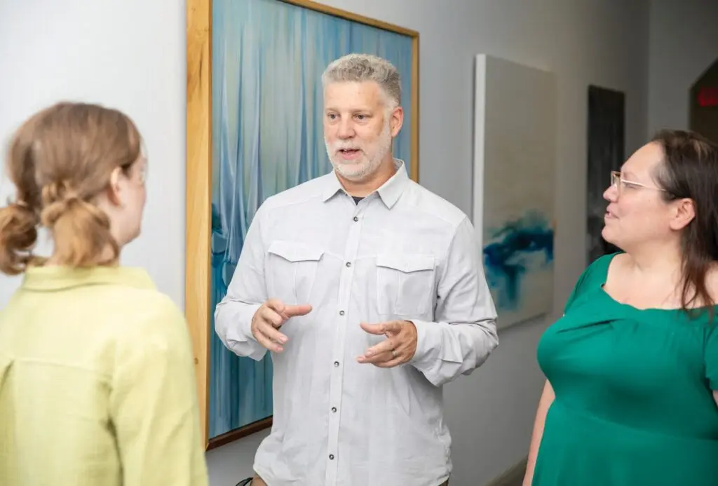 Jon Artigo, new Arts Bonita education director, chats with Gillian Cardec, marketing associate (left) and Kathy Saldivar, operations director (right).