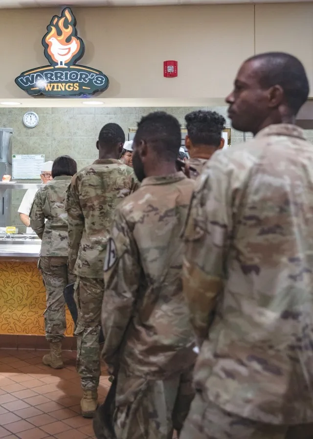 Soldiers line up at the "Warrior's Wings" station at the Headquarters Department of the Army Go for Green Action Station to receive their lunch Oct. 9 at the Operation Iraqi Freedom Dining Facility at Fort Cavazos. (U.S. Army photo by...