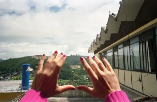 A photograph showing two hands extended in front of hte lens with a landscape in the background.