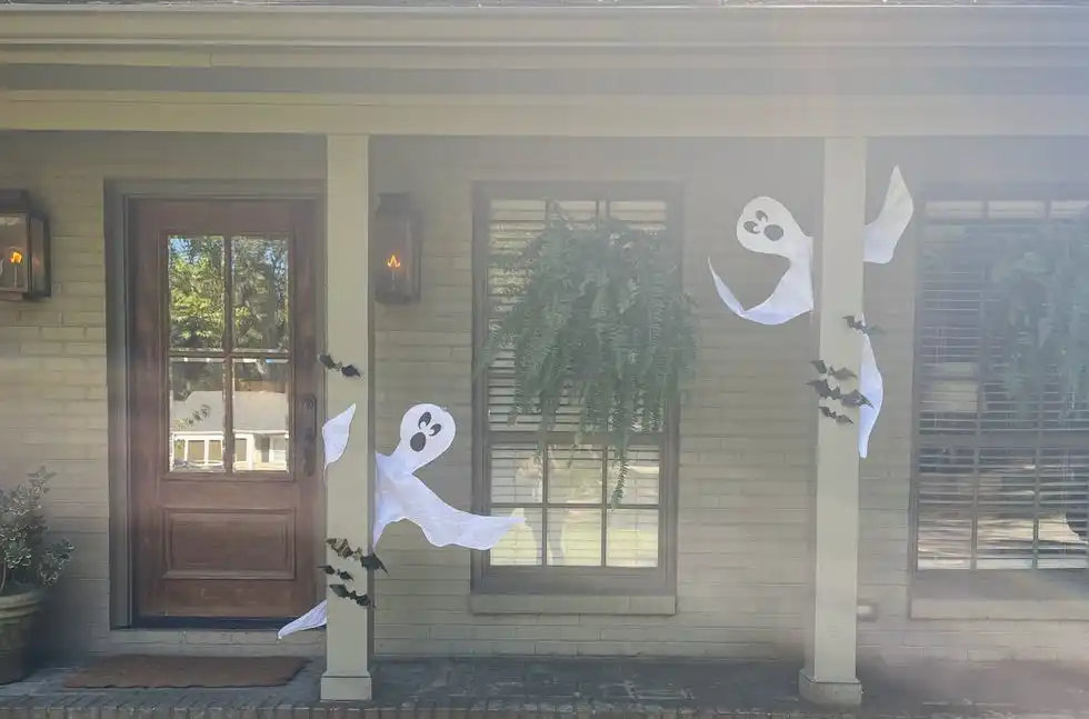 large halloween ghost decorations wrapped around two front porch pillars