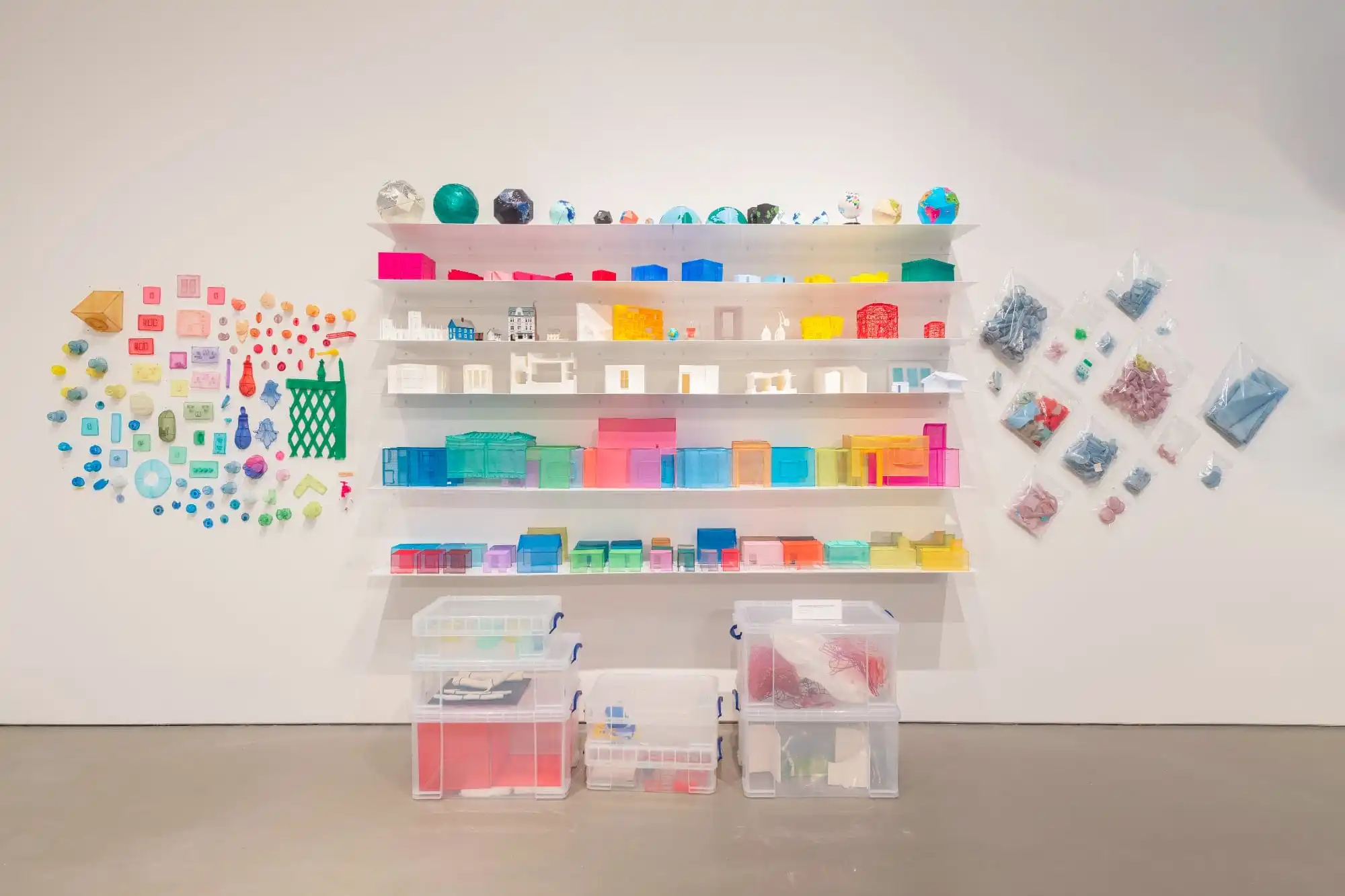 a collection of colorful fabric maquettes on shelves with collections of translucent fabric objects on either side