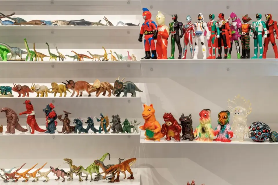 a collection of toy dinosaurs and super hero figurines on white shelves