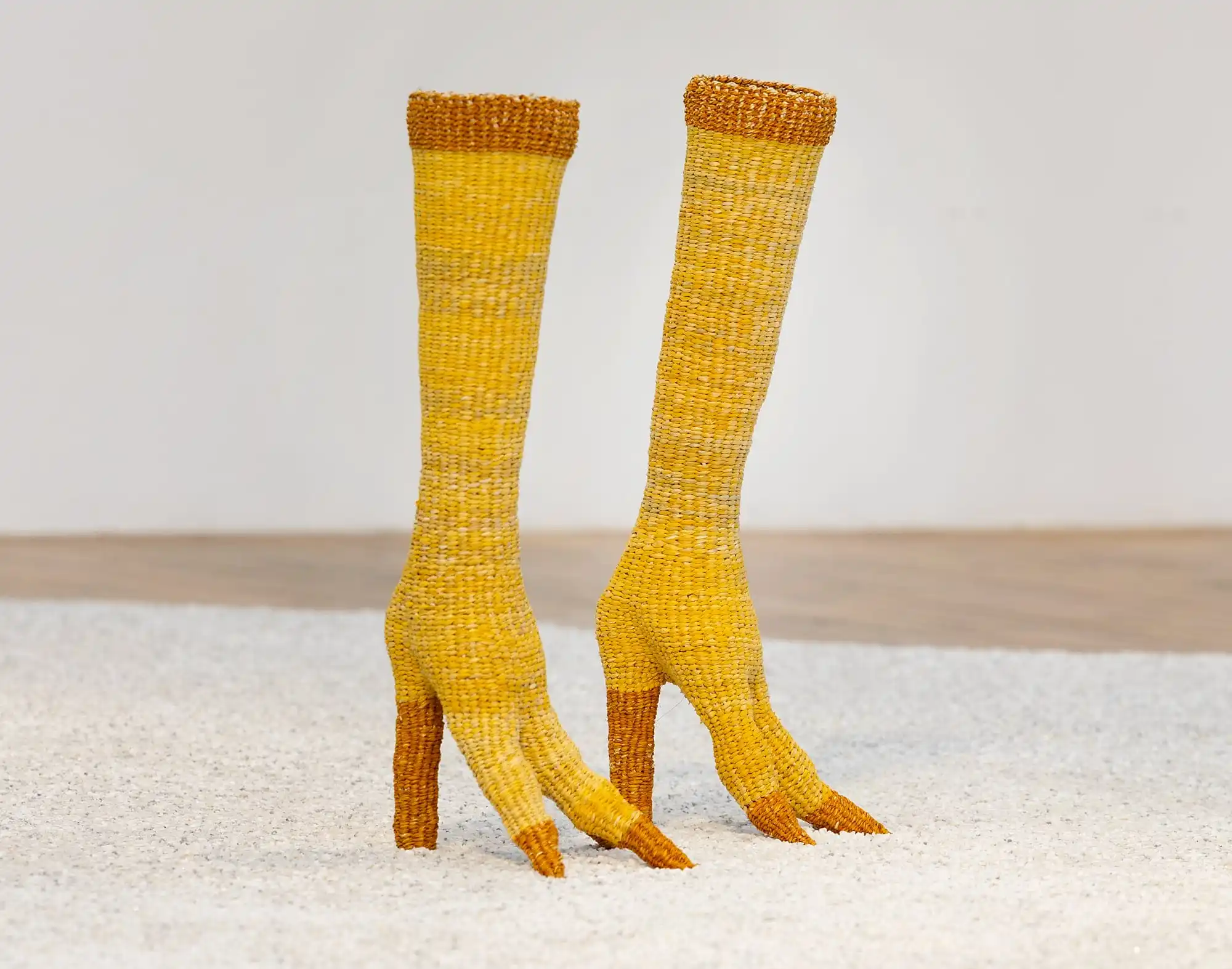 a pair of yellow woven straw boots shaped like bird legs