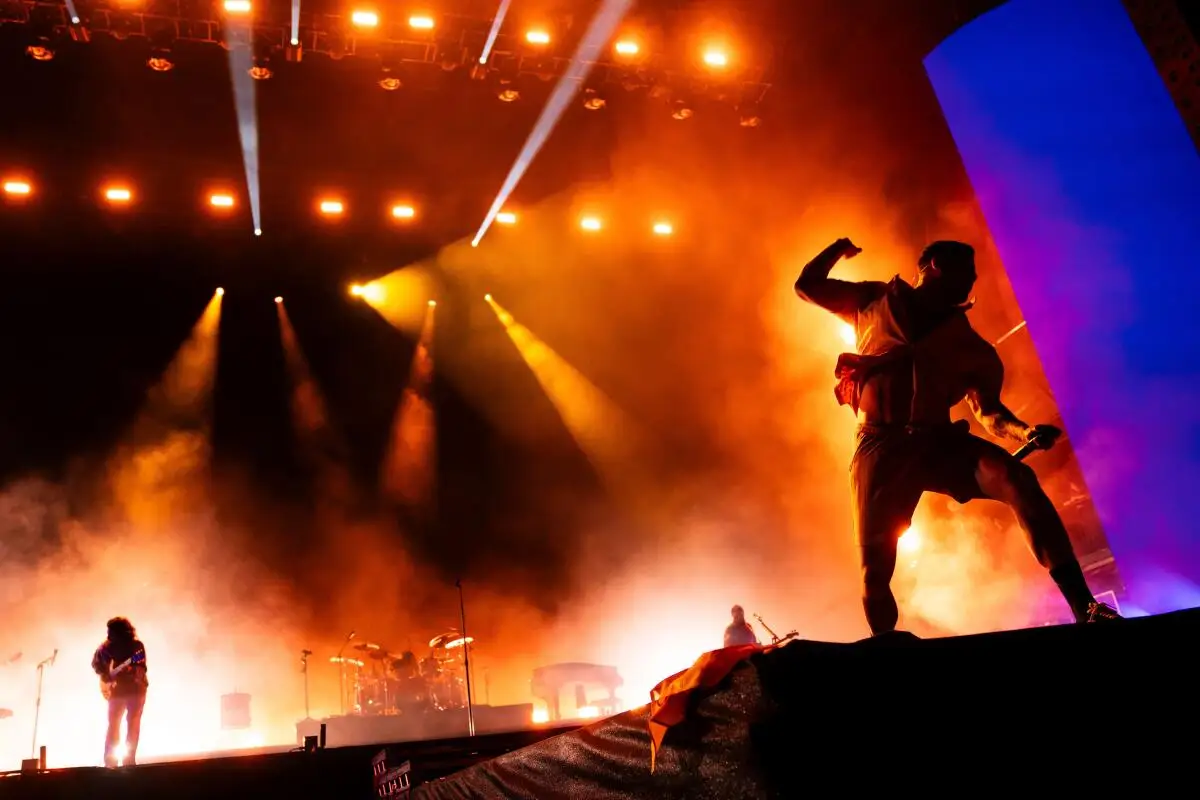 Musicians onstage against dramatic red and gold spotlights