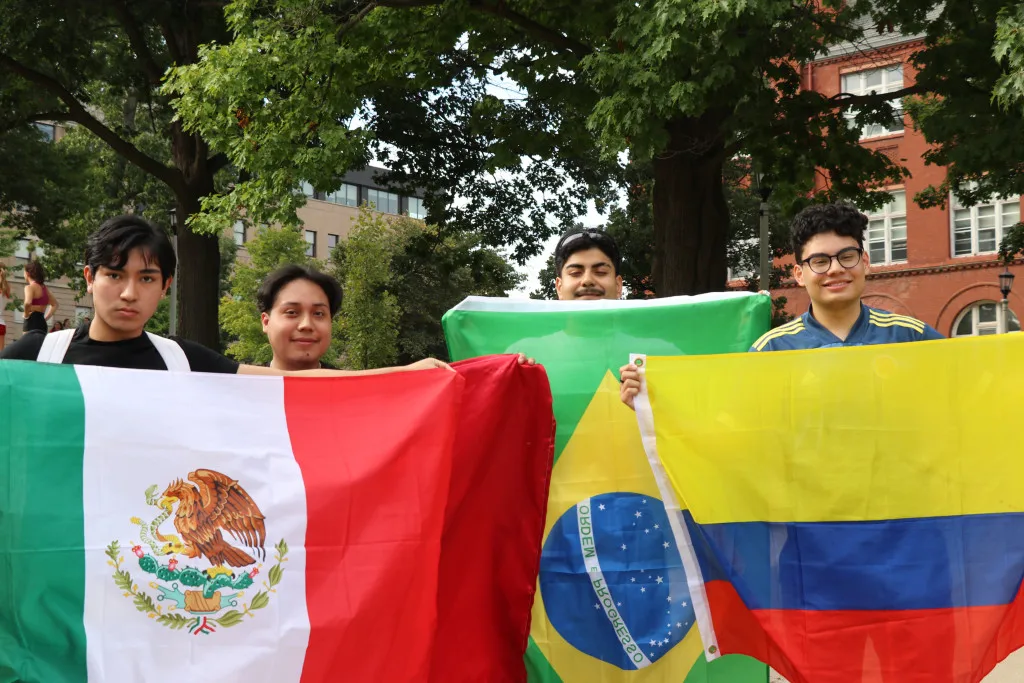 Four students hold up flags from various Latine countries, including Mexico, Brazil and Colombia.