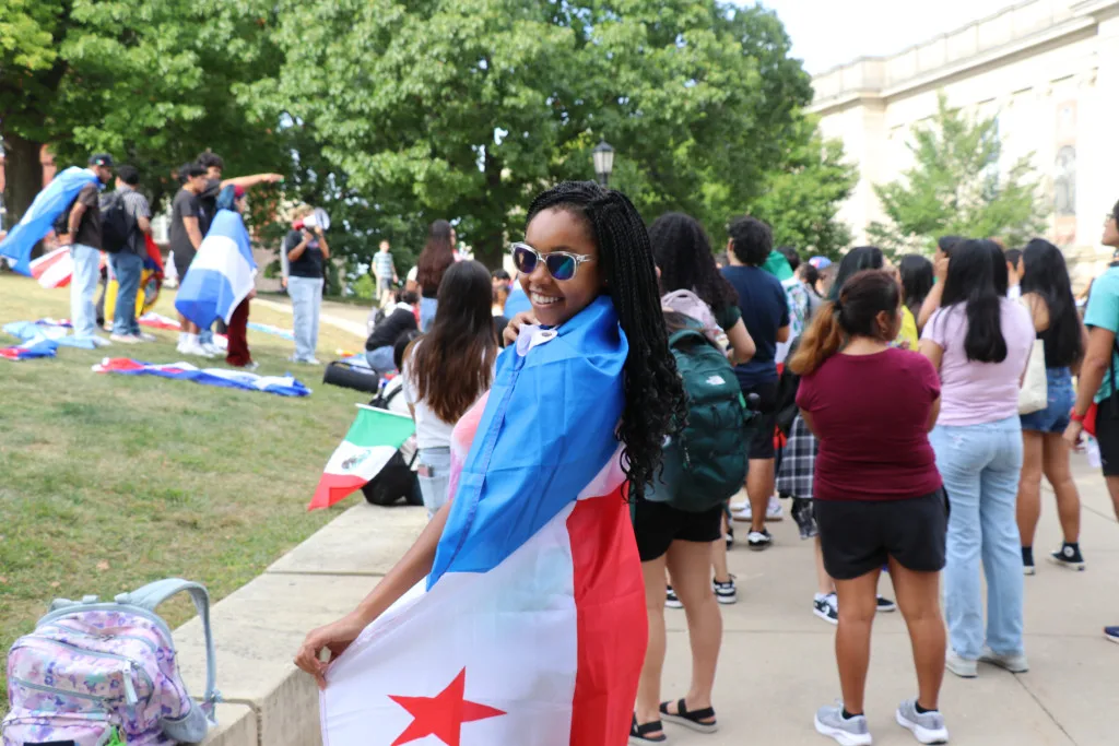 A student wears sunglasses and is wrapped in a Panamanian flag.