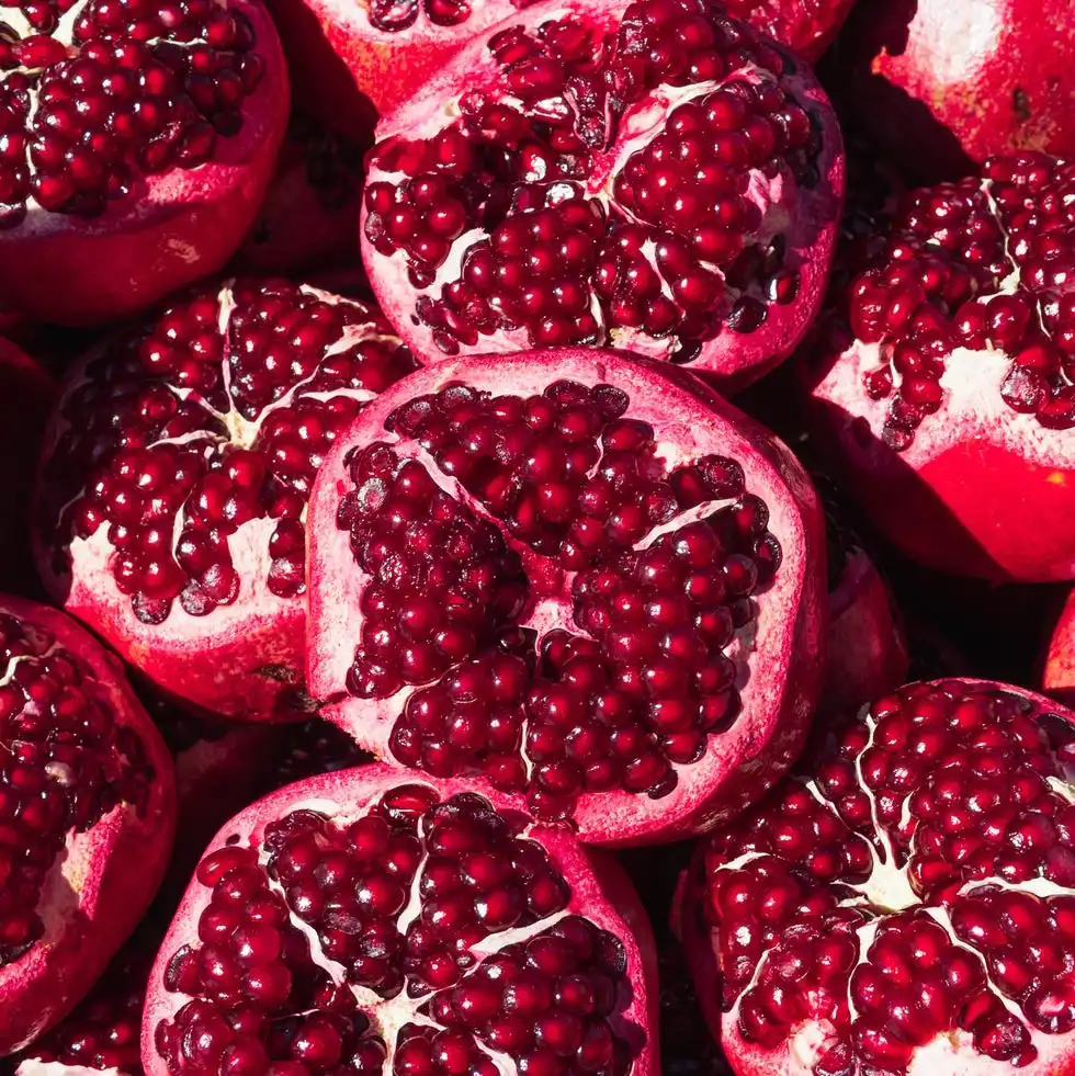 a lot of ripe red pomegranates with a cut off top, close up background