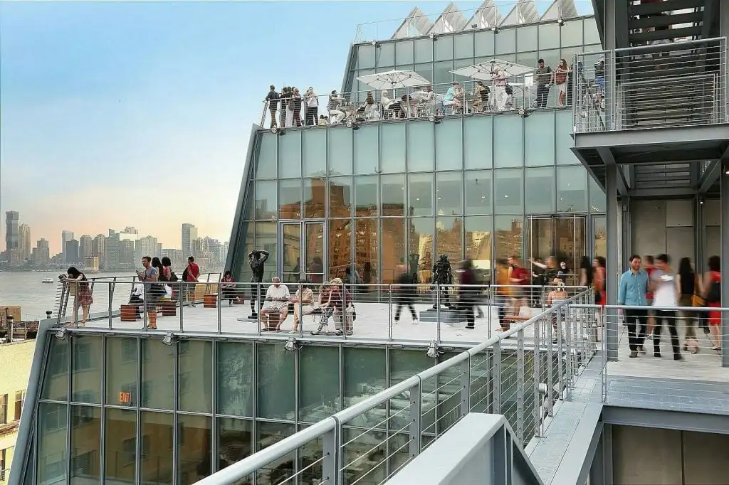 The terrace of a glass and steel building with people milling around on it