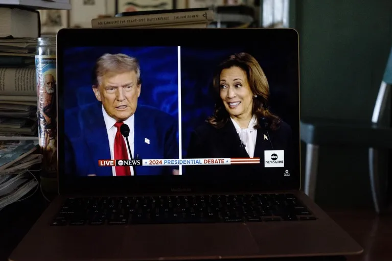 A laptop screen shows images of Donald Trump and Kamala Harris side by side during the presidential debate