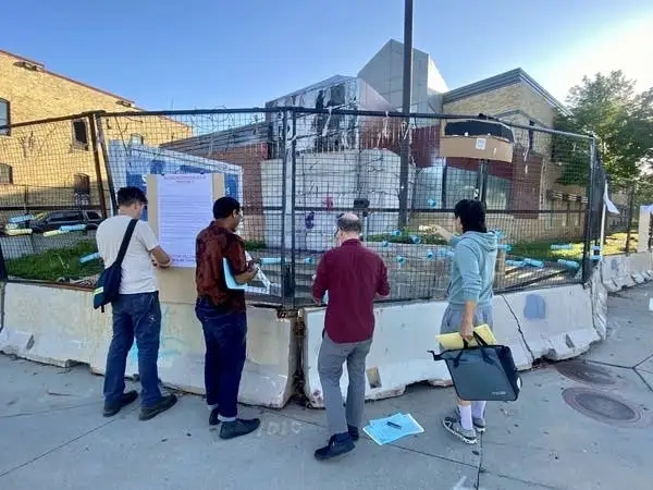 four people gather around a fenced space