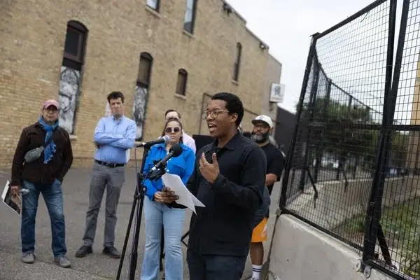 A group stands outside a fence during a press conference