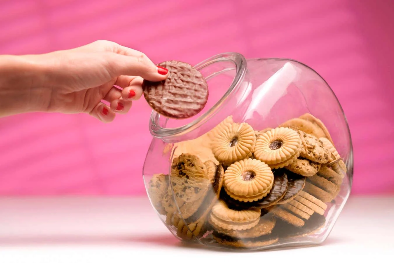 dieting woman sneaking a biscuit treat from the cookie jar