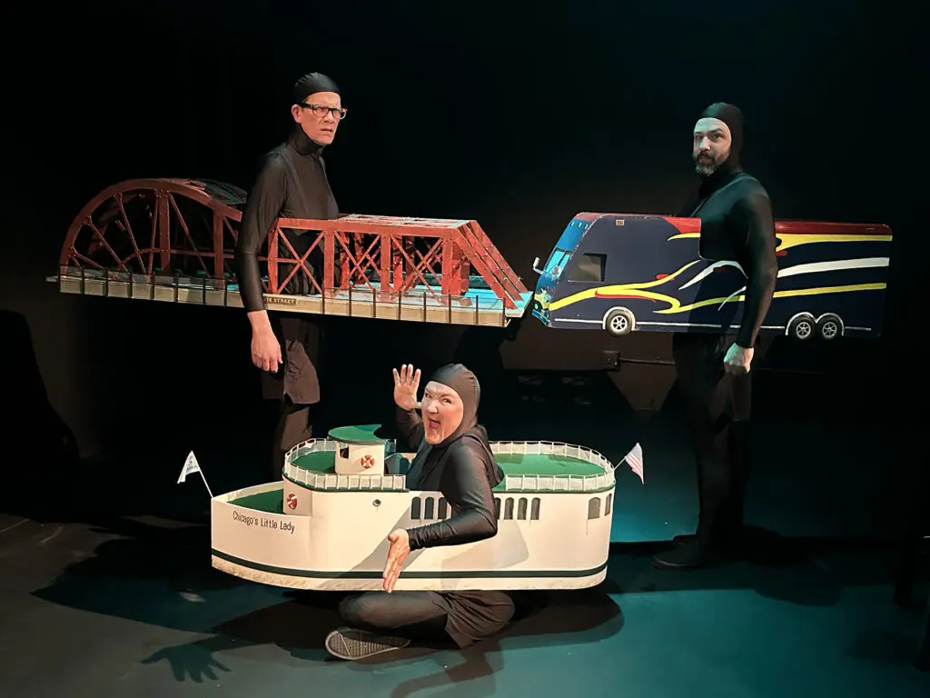 Three actors in black suits and large depictions of a bus, a bridge and a boat through their midsections