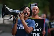 Nile Ruff, one of the dancers who was fired, prompts chants while union members and...